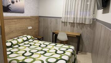 Una habitación pequeña y ordenada con una cama, un escritorio y una silla.