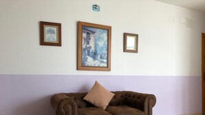 A room with a brown leather sofa, a large framed painting, and a WiFi sign on the wall. - Hostal 82 (Olias del Rey)