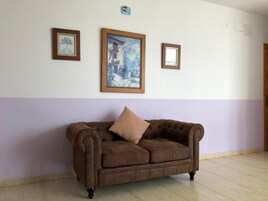 Una habitación con un sofá de cuero marrón, un cuadro grande enmarcado y un cartel de WiFi en la pared.