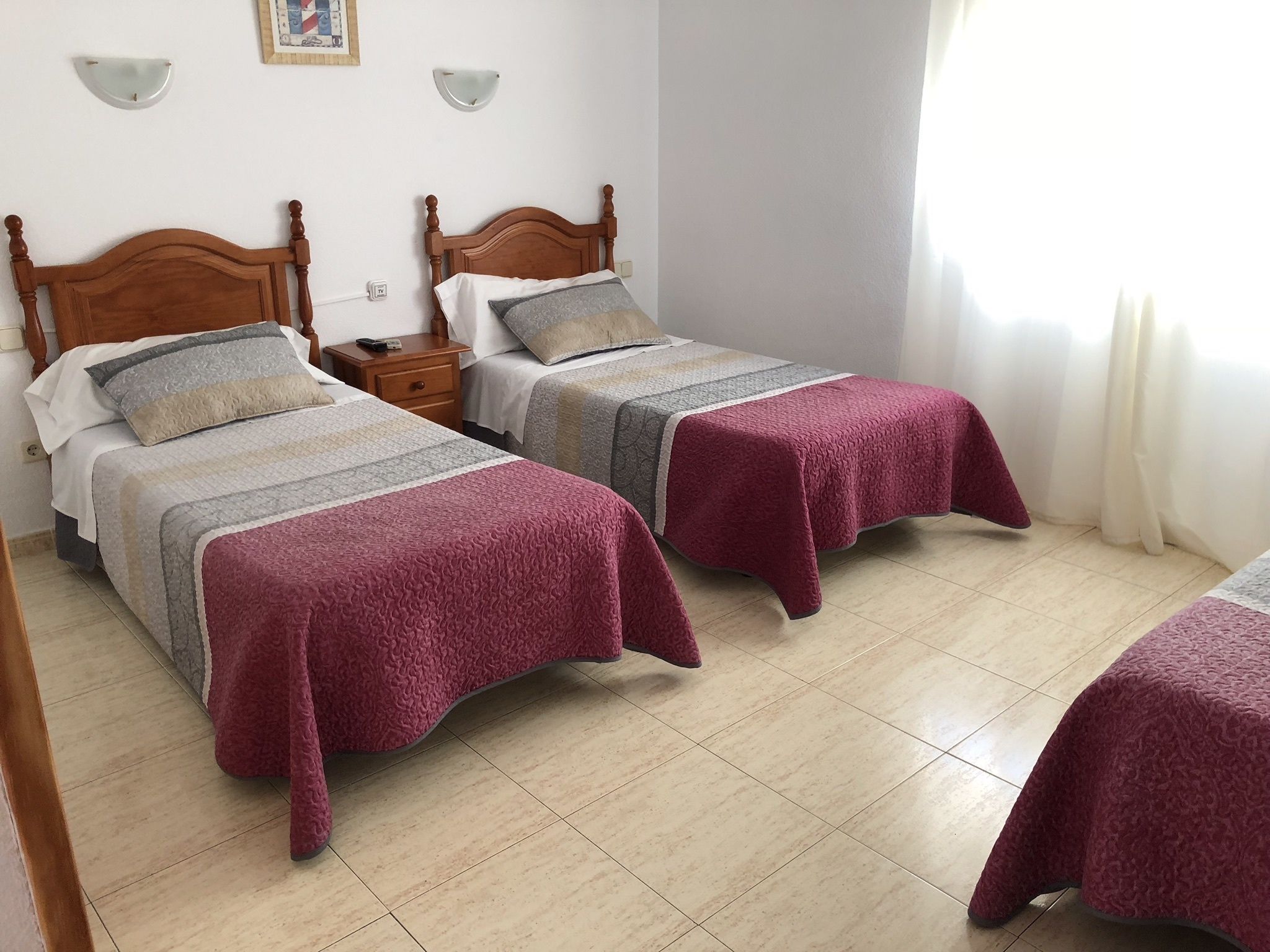 Une chambre d’hôtel avec deux lits, chacun doté d’une tête de lit en bois, d’une table de chevet et d’un luminaire fixé au mur.