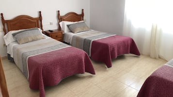 Une chambre d’hôtel avec deux lits, chacun doté d’une tête de lit en bois, d’une table de chevet et d’un luminaire fixé au mur.