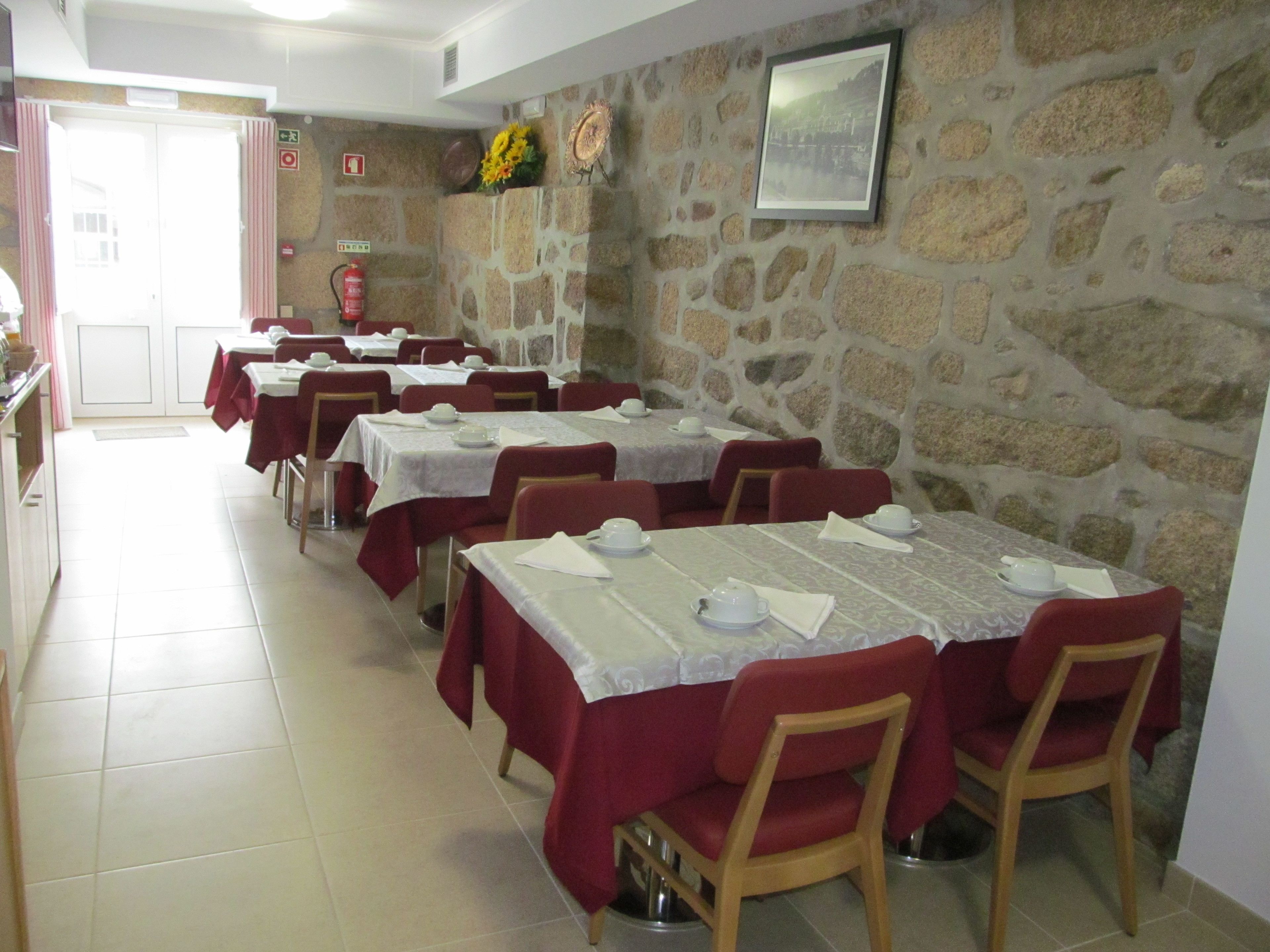 Un comedor con varias mesas dispuestas para el servicio, paredes de piedra y un cuadro en la pared.