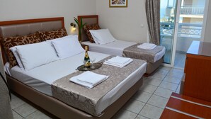 Une chambre d’hôtel avec deux lits, un balcon et vue sur la mer.