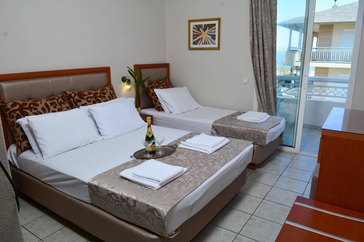 A hotel room with two beds, a balcony, and a view of the sea.