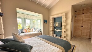 A bedroom with a large bed, a window with a view, a stone shelf, and a wardrobe. - Cassiopeia Hotel Alacati (Cesme)