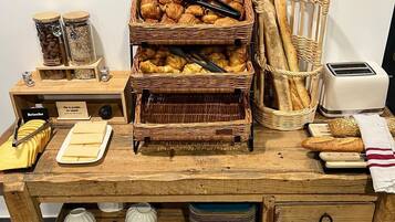 A wooden buffet table with various food items, including pastries and bread, and a toaster.