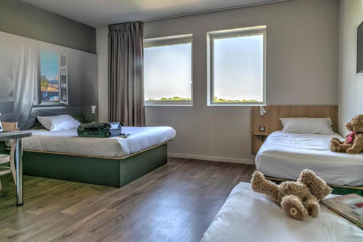 Een hotelkamer met twee bedden, een bureau en een groot raam.