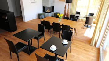 Un comedor moderno con una mesa de madera y sillas negras, una chimenea y vistas al exterior.