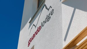 Un bâtiment sur lequel on peut lire, en lettres rouges et noires, l’inscription « Guarda lodge ».