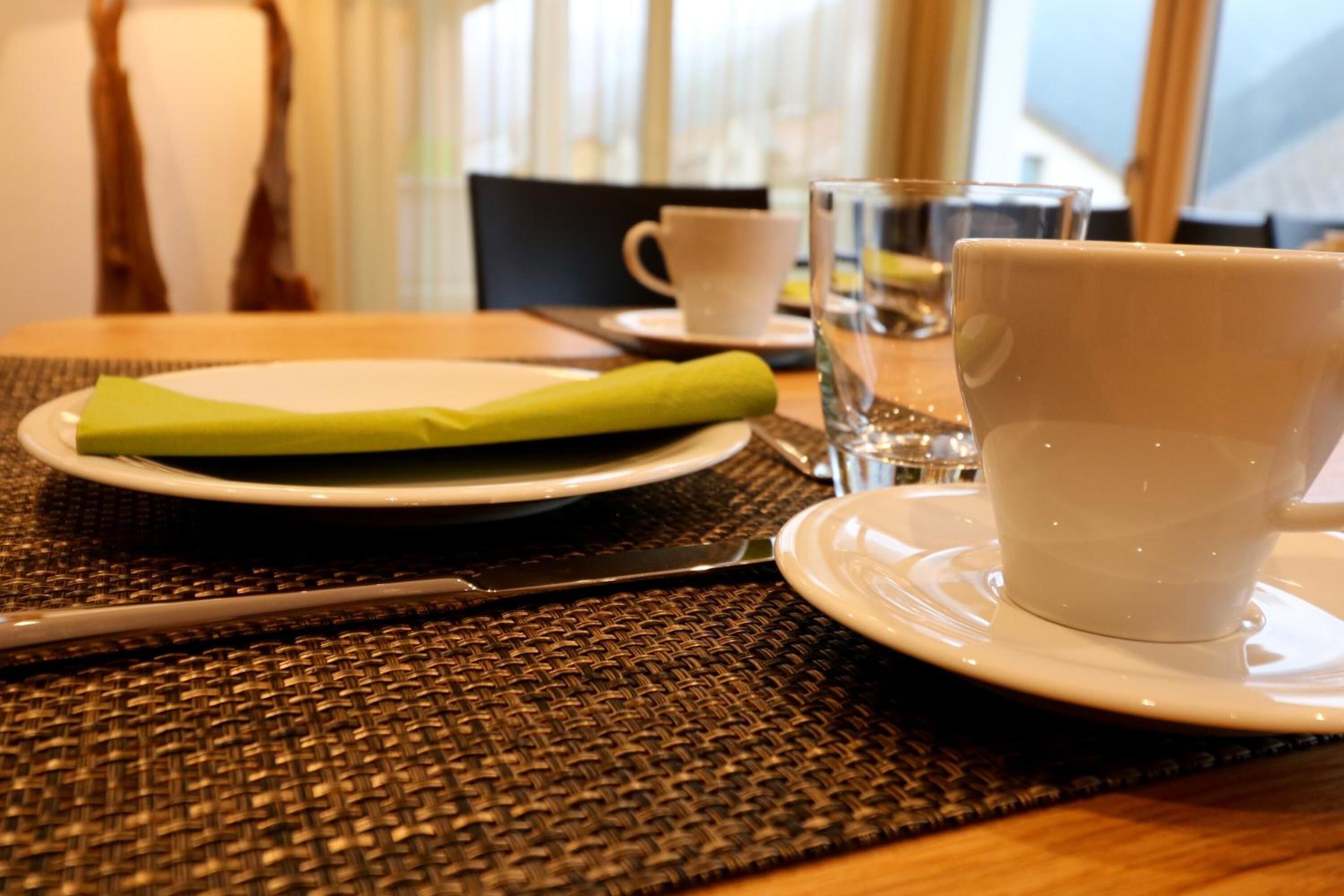 A table set with a plate, a green napkin, a cup, and a glass of water.