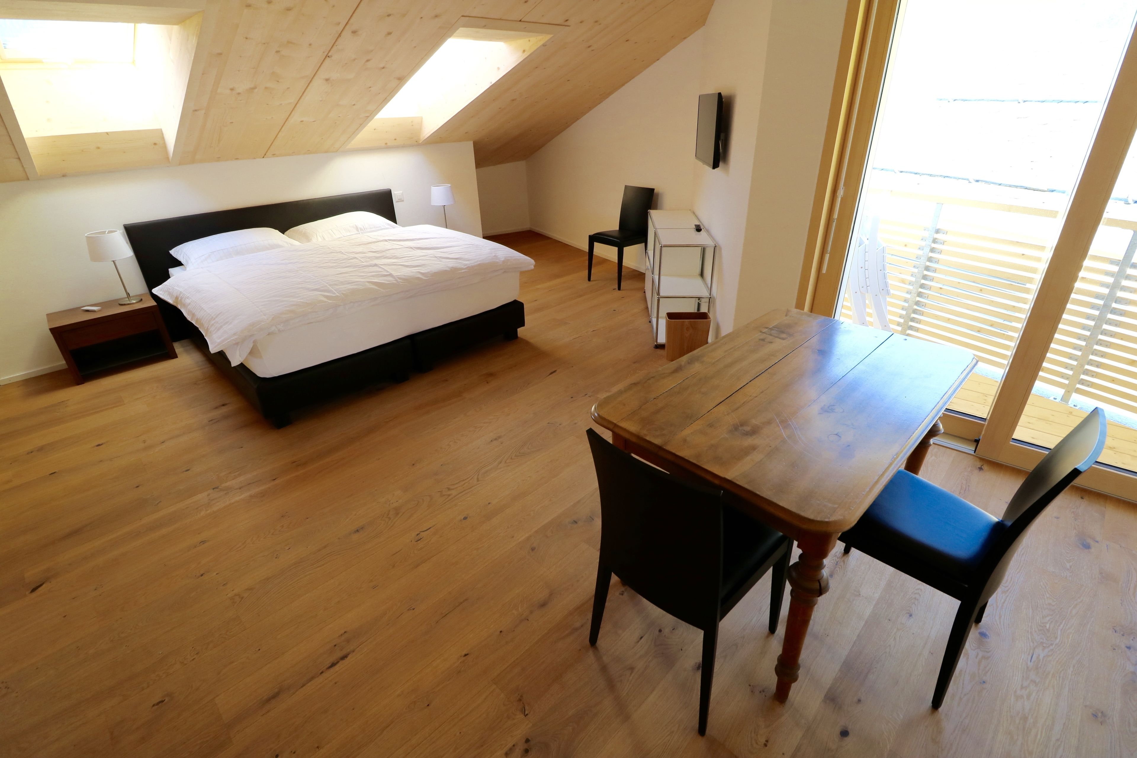 Une chambre à coucher avec un lit, une table en bois et une chaise.