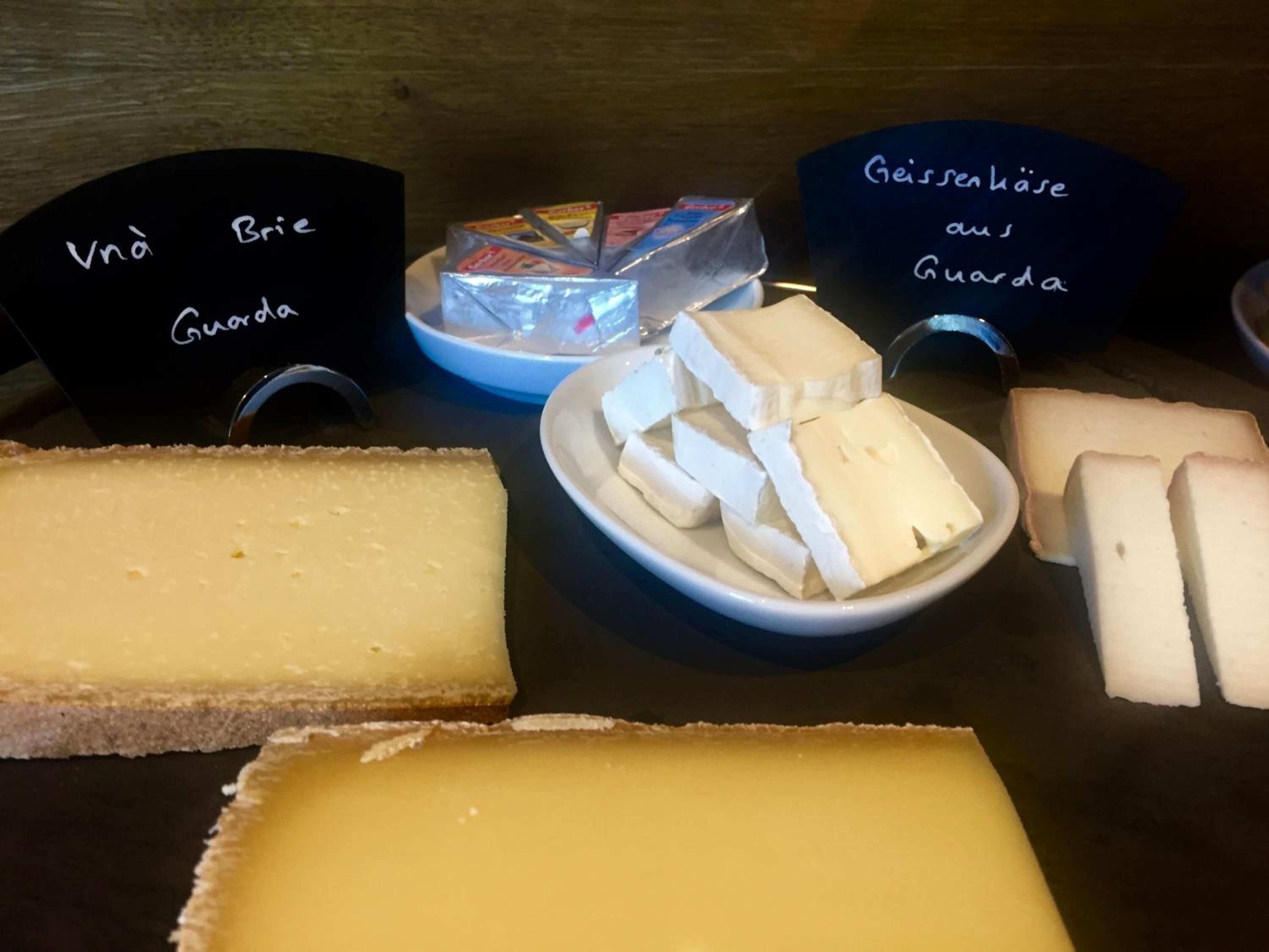 Various types of cheese displayed on a table with labels indicating their names.