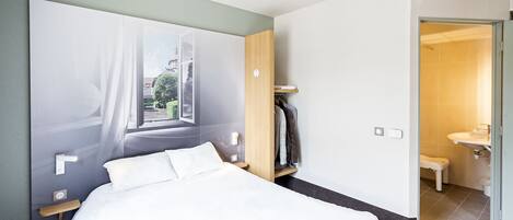 A modern hotel room with a large bed, a wardrobe, and a bathroom visible through an open door.