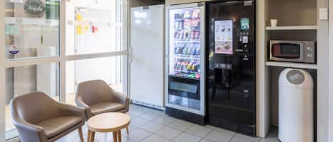 Un interior moderno con una máquina expendedora, un microondas y una zona de estar.