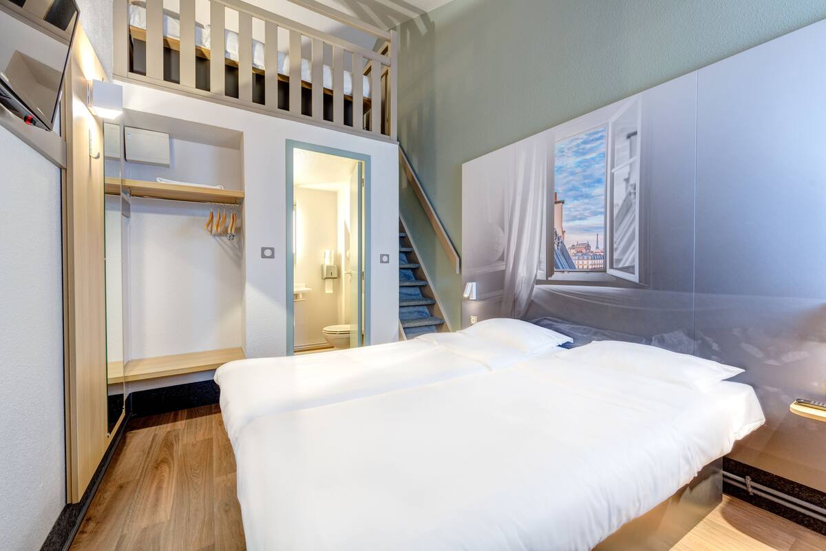 A bedroom with a bed, a walk-in closet, and a staircase leading to an upper bunk.