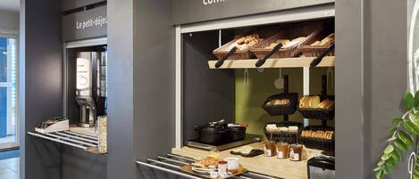 A breakfast station with bread, pastries, and beverages.