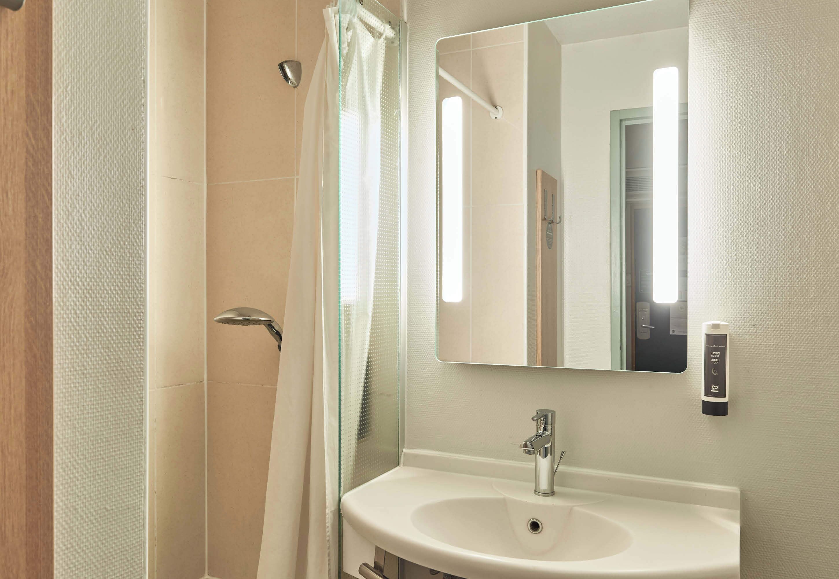 A bathroom with a shower, a sink, and a mirror.
