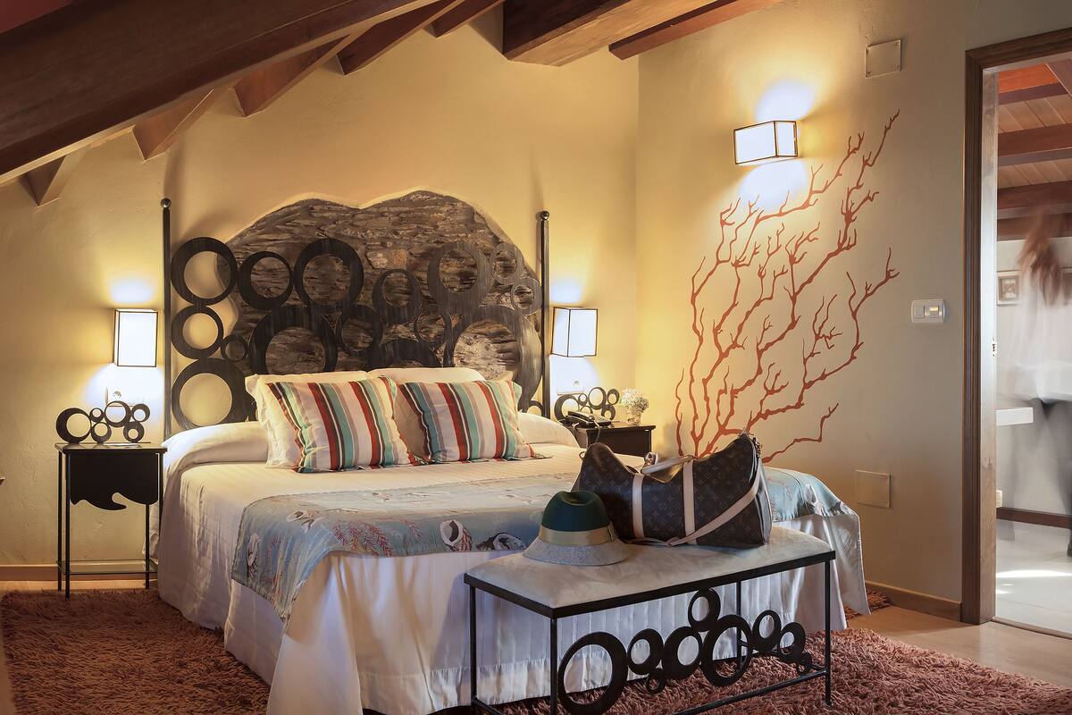 A bedroom with a bed, a chair, a desk, and a nightstand.