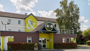 A B&B hotel with a yellow facade, a prominent B&B logo, and a brown entrance. - B&B HOTEL Paris Nord Villepinte (Villepinte)