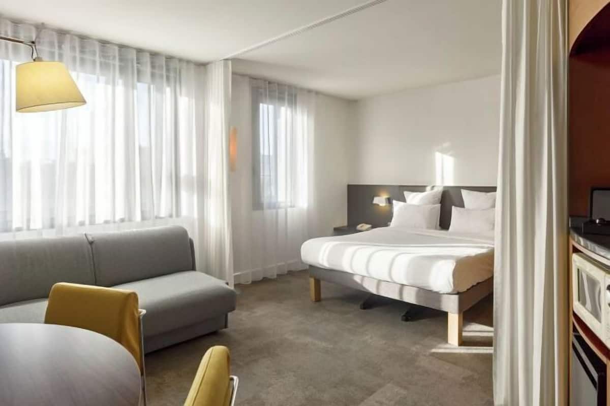 Een hotelkamer met een bed, een slaapbank, een bureau en een televisie.