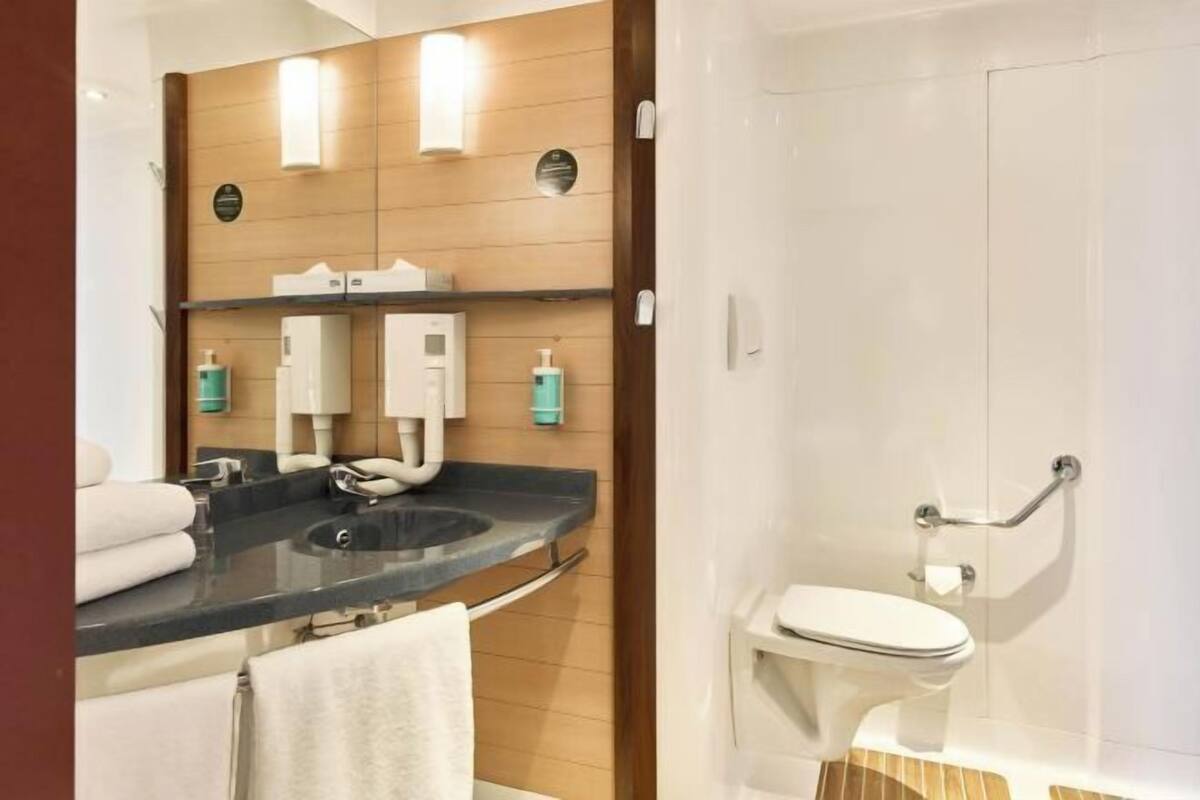 Een moderne badkamer met een wastafel, spiegel, handdoekhouder en toilet.