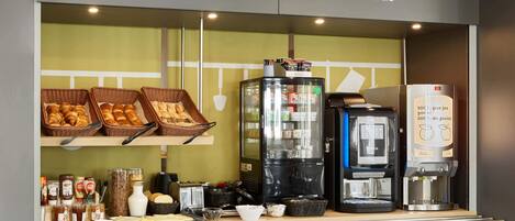 A breakfast counter with baskets of croissants, a coffee machine, and various breakfast items.