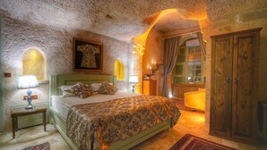 Quarto com uma cama grande, um guarda-roupa de madeira e uma mesinha com abajur.