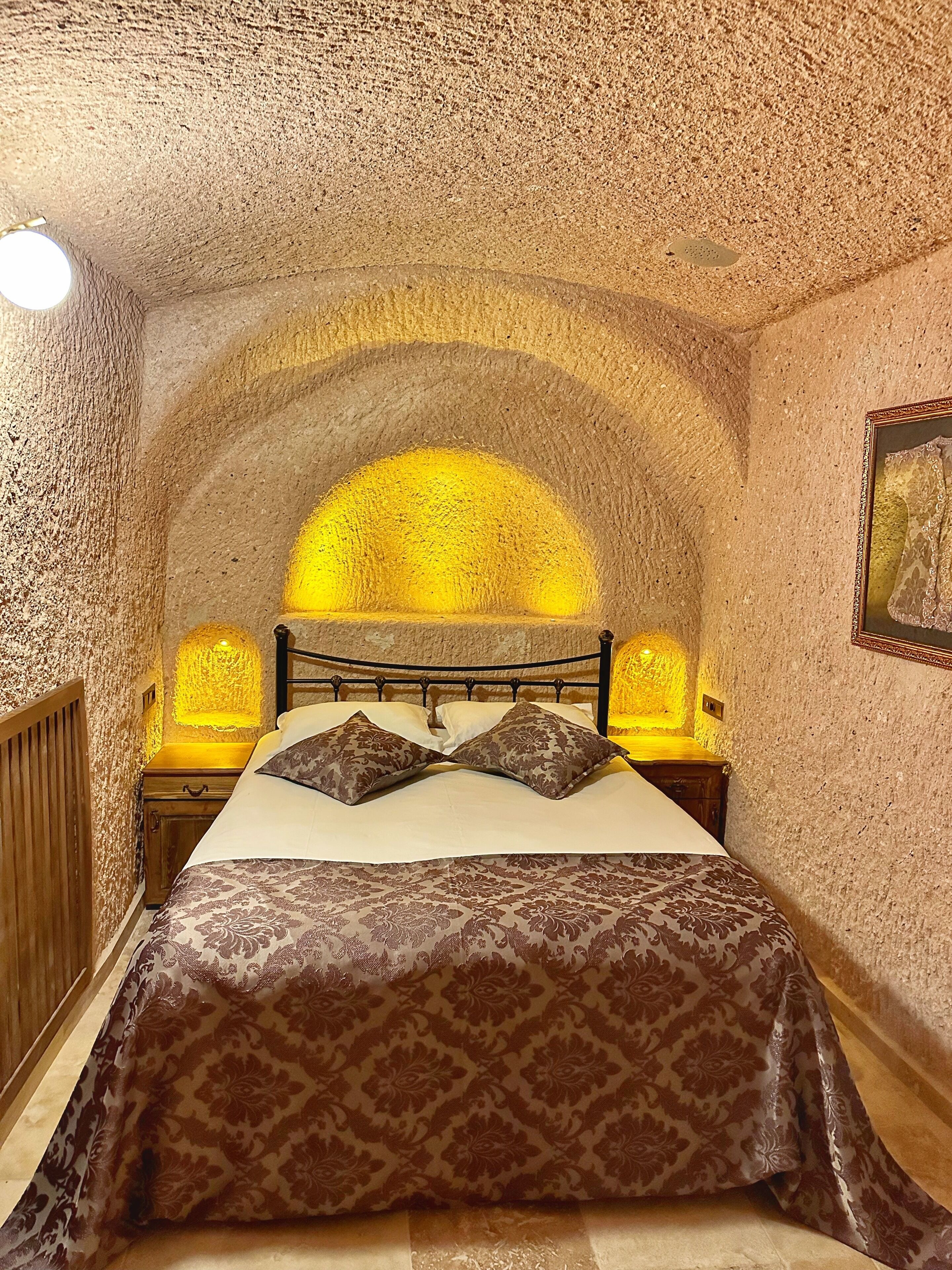 A bedroom with a bed, patterned bedspread, and a unique arched ceiling.