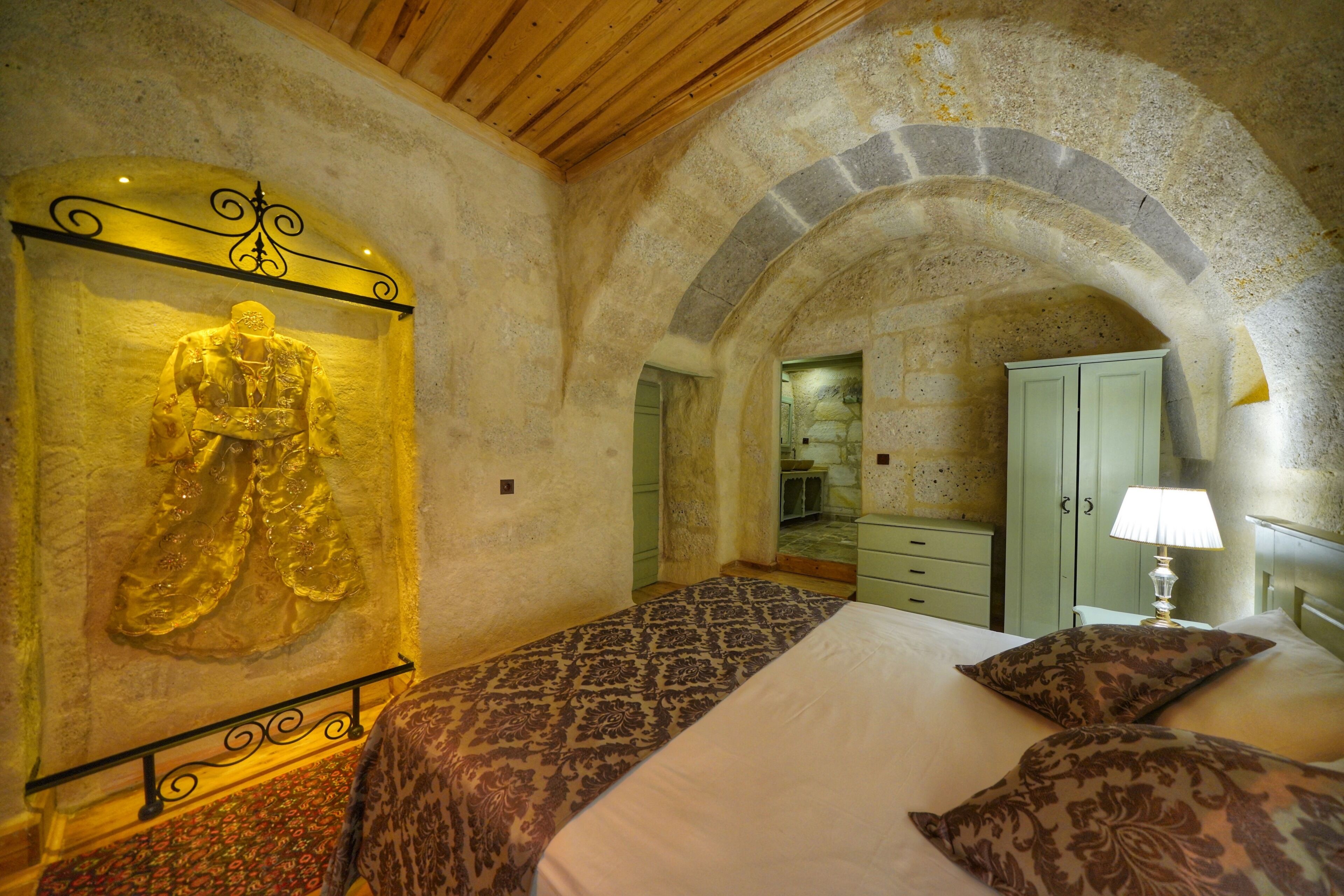 Ein Schlafzimmer mit einem Bett, einem gemusterten Bettbezug, einer Wandskulptur, einem Spiegel und einer Lampe.