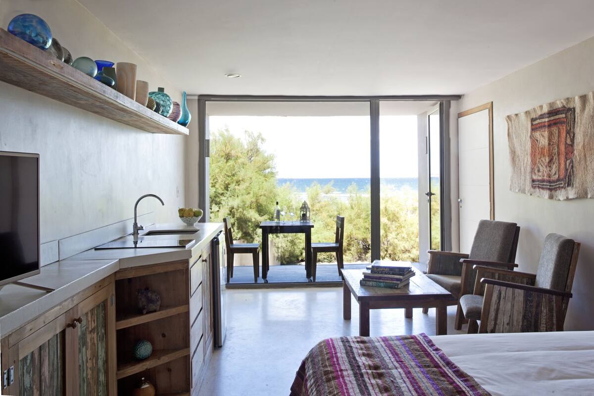 A bedroom with a bed, a desk, a chair, a window, and a view of the outdoors.
