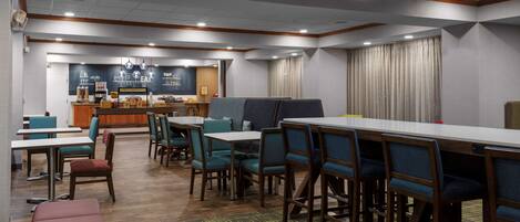 A hotel dining area with tables and chairs, a counter with a menu, and a bar.