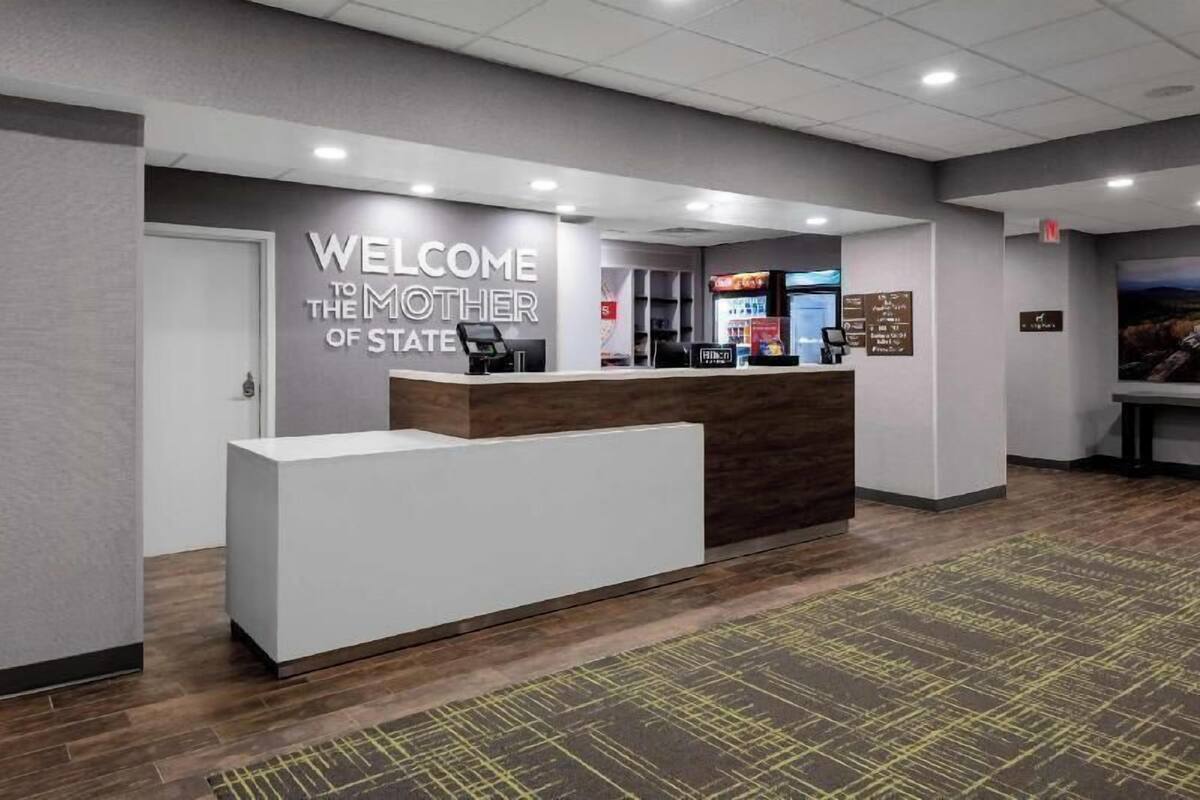 A reception desk with a 'WELCOME TO THE MOTHER OF STATE' sign, a counter, and a wall-mounted menu board.