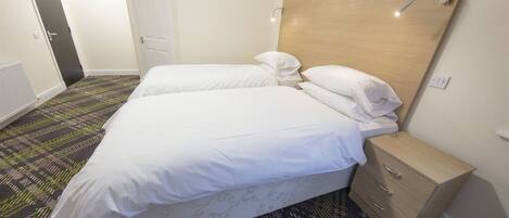 Habitación de hotel con una cama grande, una mesita de noche, un armario y una alfombra estampada.
