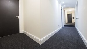 A hallway with a dark carpet, white walls, and a black door marked with the number 3. - The Bay Horse (Hamilton)