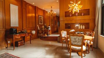 A spacious room with a wooden dining table, chairs, a chandelier, and a large window.