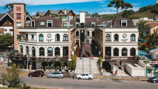 Um edifício histórico com uma escadaria central e vários andares, com janelas em arco e uma torre do relógio imponente.