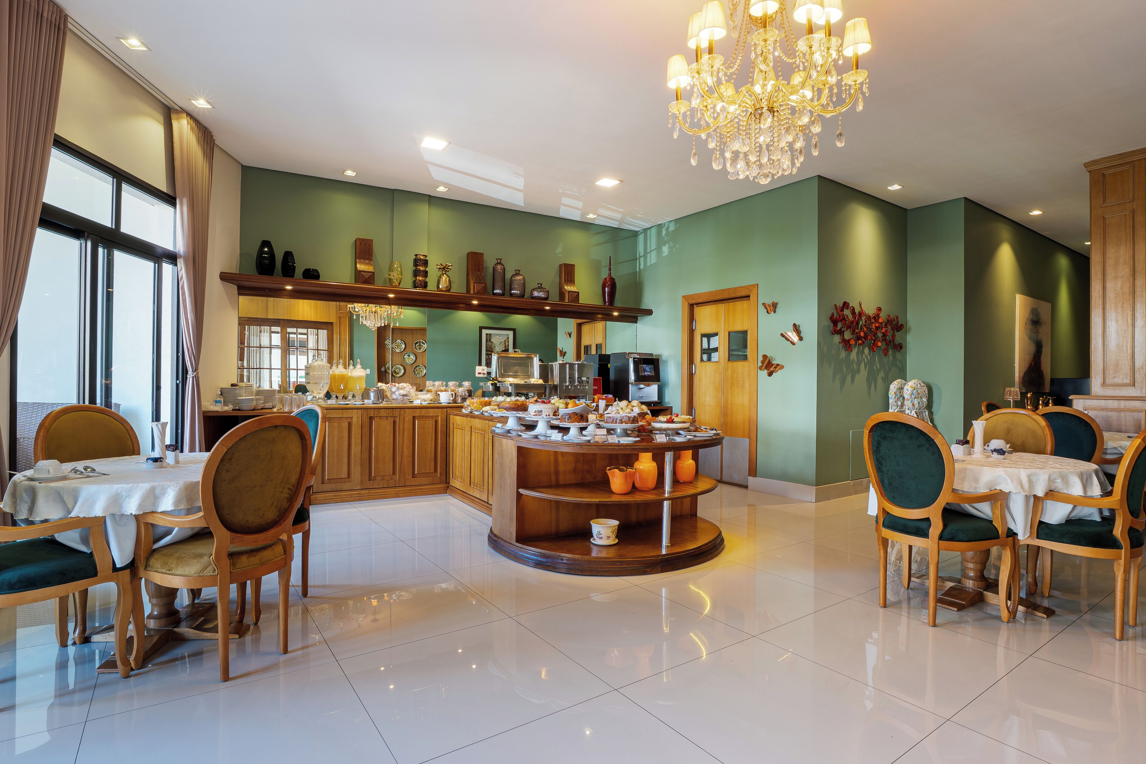 A spacious dining area with a central island, wooden chairs, and a chandelier.