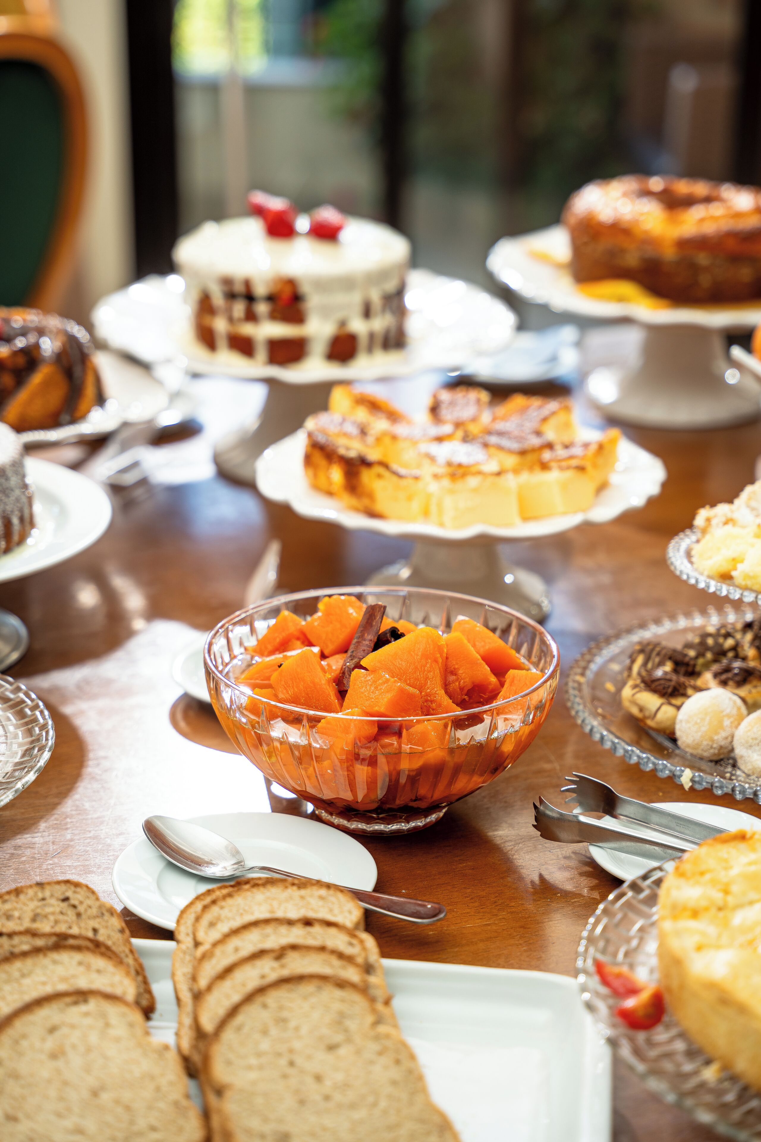 Ein Tisch mit verschiedenen Desserts und Brot, darunter eine Schale mit Obstscheiben und mehrere Kuchen.
