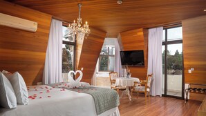 Quarto com cama, lustre, televisão e varanda.