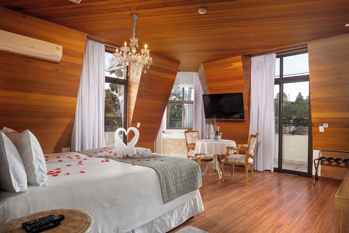 Un dormitorio con cama, candelabro, televisor y balcón.