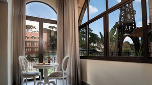 Quarto com uma janela grande, duas cadeiras, uma mesa pequena e vista para uma torre do relógio.