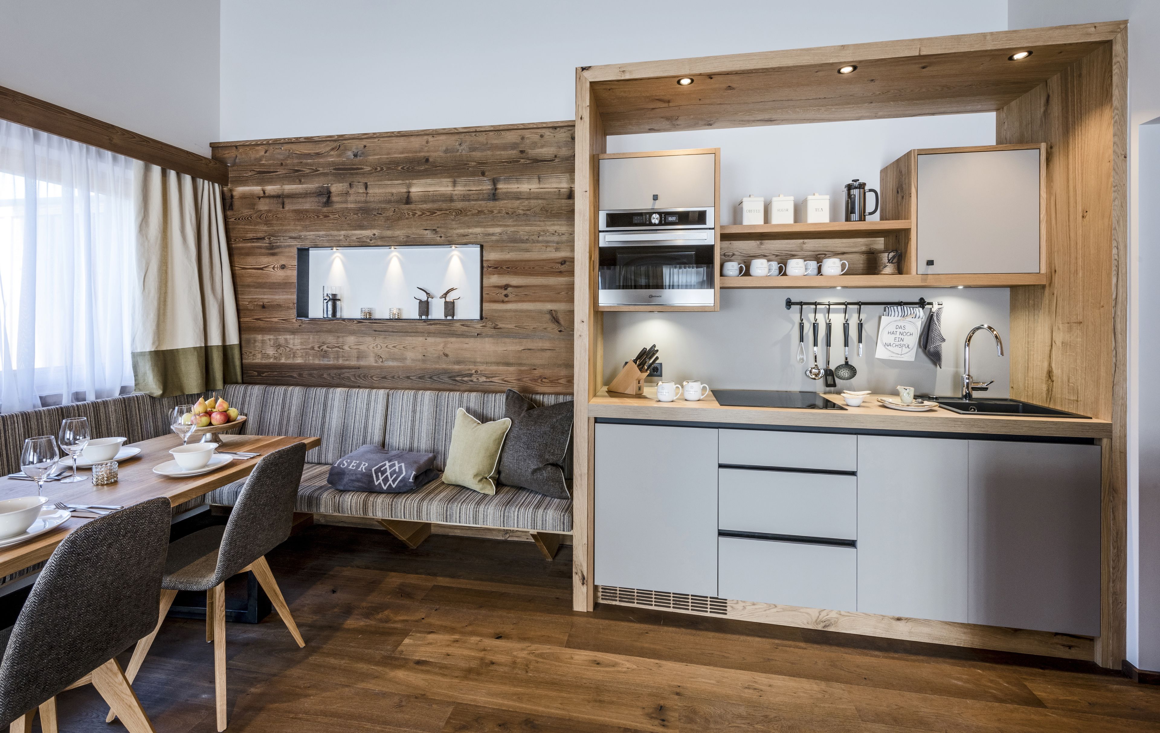 Una cocina moderna con una pared de acento de madera, electrodomésticos integrados y un comedor con banco y mesa.