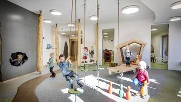 Children can play safely in this enclosed play area featuring swings, a climbing wall, and a bowling alley.