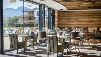 Un comedor moderno con pisos de madera, ventanas amplias y vistas a montañas.