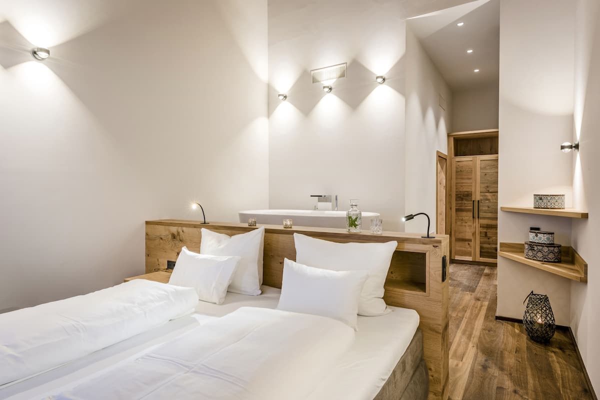 Un dormitorio moderno con cabecera de madera, una cama grande con ropa de cama blanca, un tocador empotrado con espejo y un armario de madera.