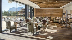 Un espace de restauration intérieur doté d’un plafond en bois et de grandes fenêtres offrant une vue sur les montagnes.