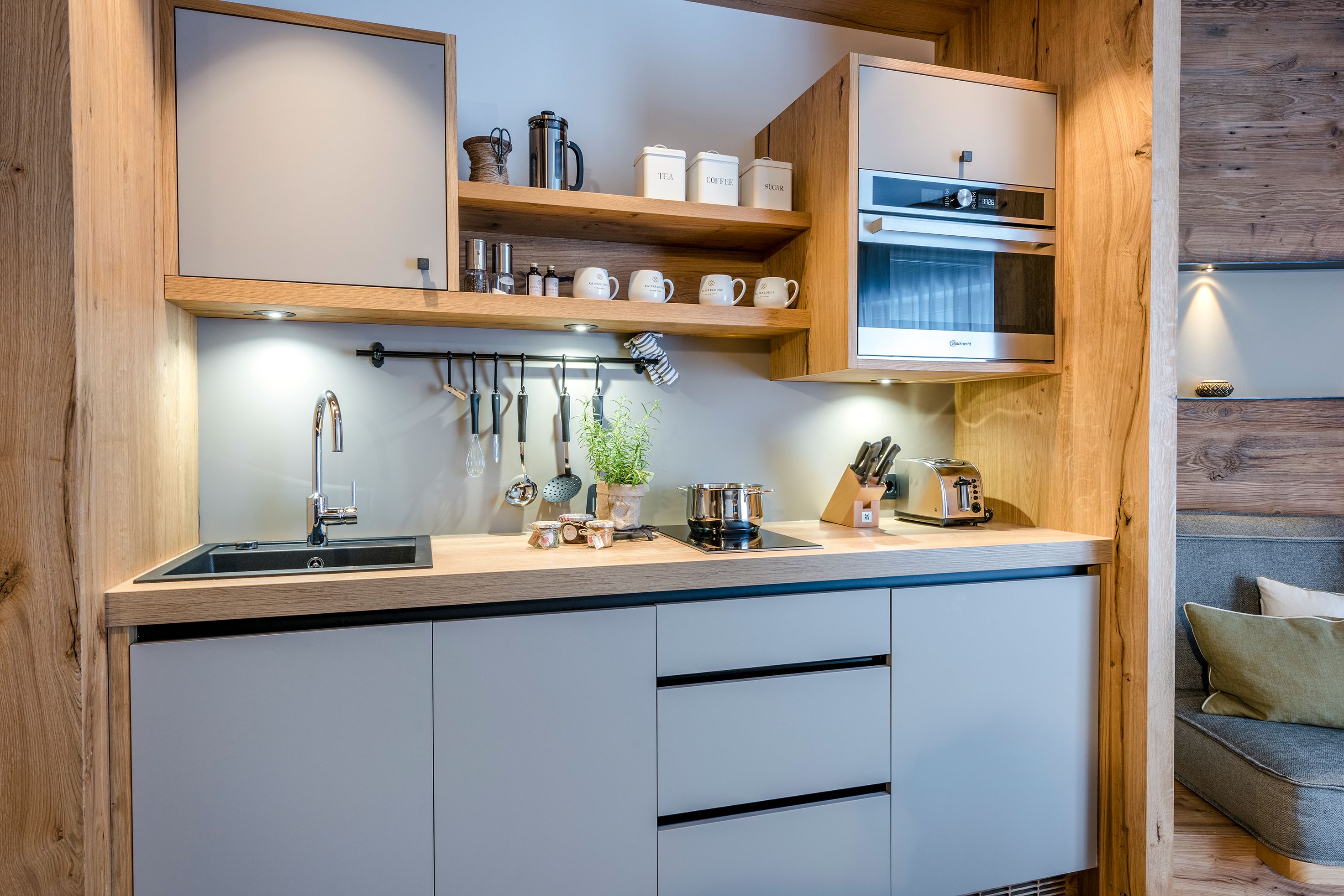 Una cocina moderna con armarios de madera, un lavamanos de acero inoxidable y un horno empotrado.