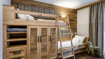 Een stapelbed met een ladder, een houten garderobe en een schommelpaard.