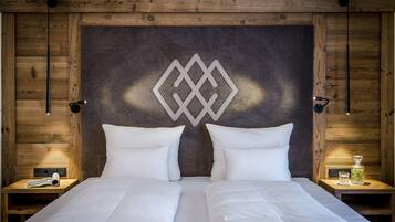 Una cama doble con sábanas blancas, un cabecero de madera con diseño geométrico y dos mesitas de noche con lámparas y una botella.