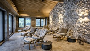 Un espace de détente avec des fauteuils en osier, des murs en pierre et de grandes fenêtres.